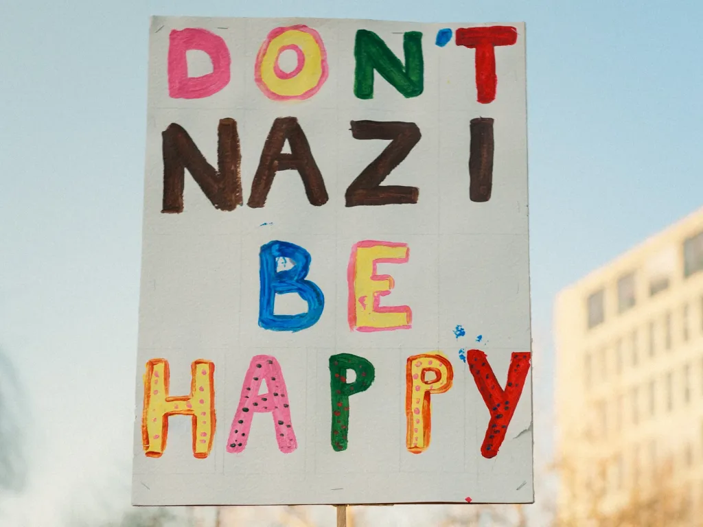 Buntes Schild mit der Aufschrift "Don´t Nazi, be happy"