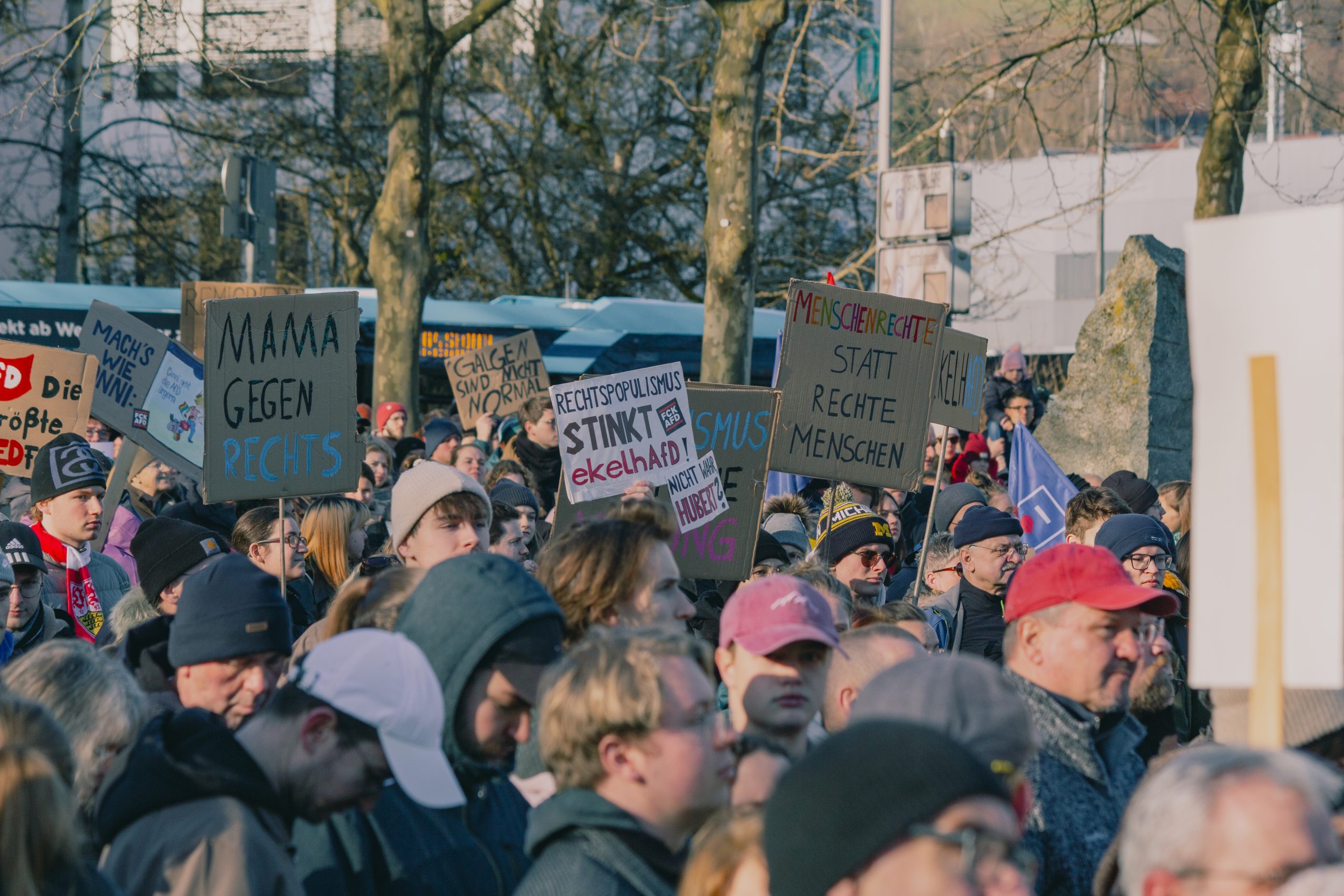 Menschen auf einer Kundgebung mit bunten Schildern gegen Rechtsextremismus und Rechtspopulismus